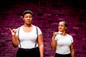 Two women pretend to eat cucumber sandwiches